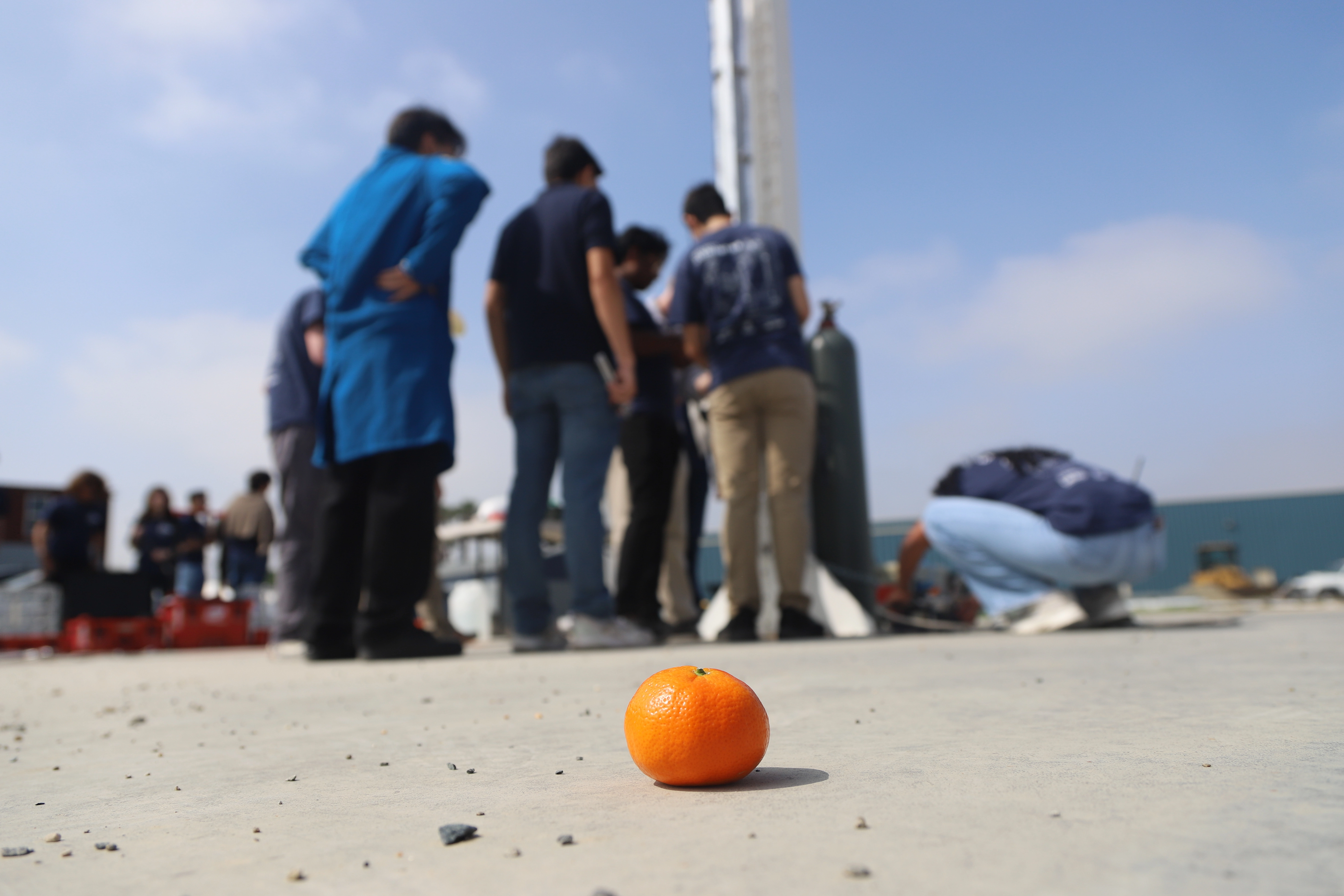 HSP students preparing their rocket, with an orange in the foreground